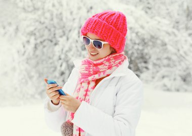 Karlı kış gün giyen smartphone kullanarak mutlu gülümseyen kadın