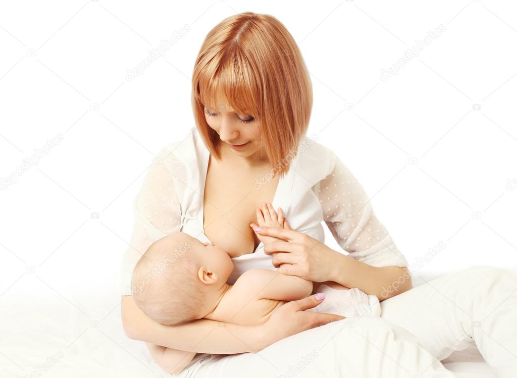 Happy smiling mother feeding breast her baby on bed 