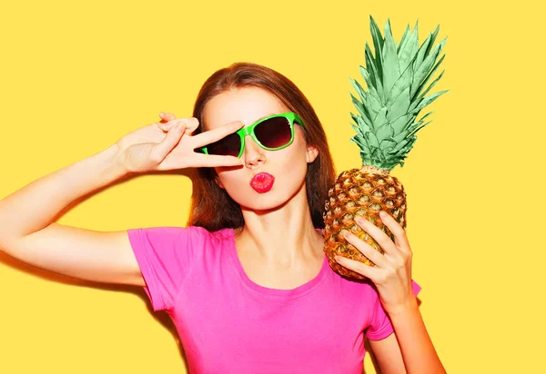 Fashion portrait cool girl in sunglasses and pineapple over yell