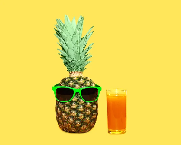 Ананас з сонцезахисними окулярами та скляним фруктовим соком на жовтому фоні — стокове фото