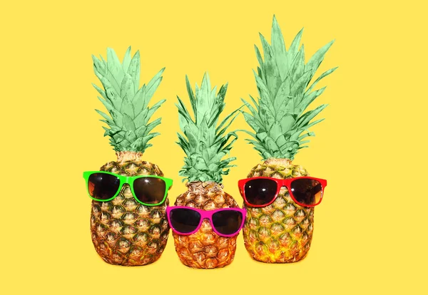 Tre ananas con occhiali da sole su sfondo giallo, colorato a — Foto Stock