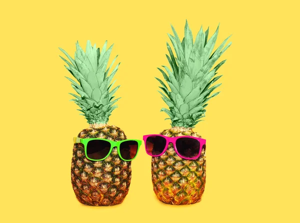 Due ananas con occhiali da sole su sfondo giallo, colorato ana — Foto Stock