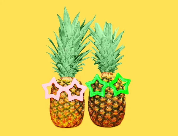 Due ananas con occhiali da sole su sfondo giallo, colorato ana — Foto Stock