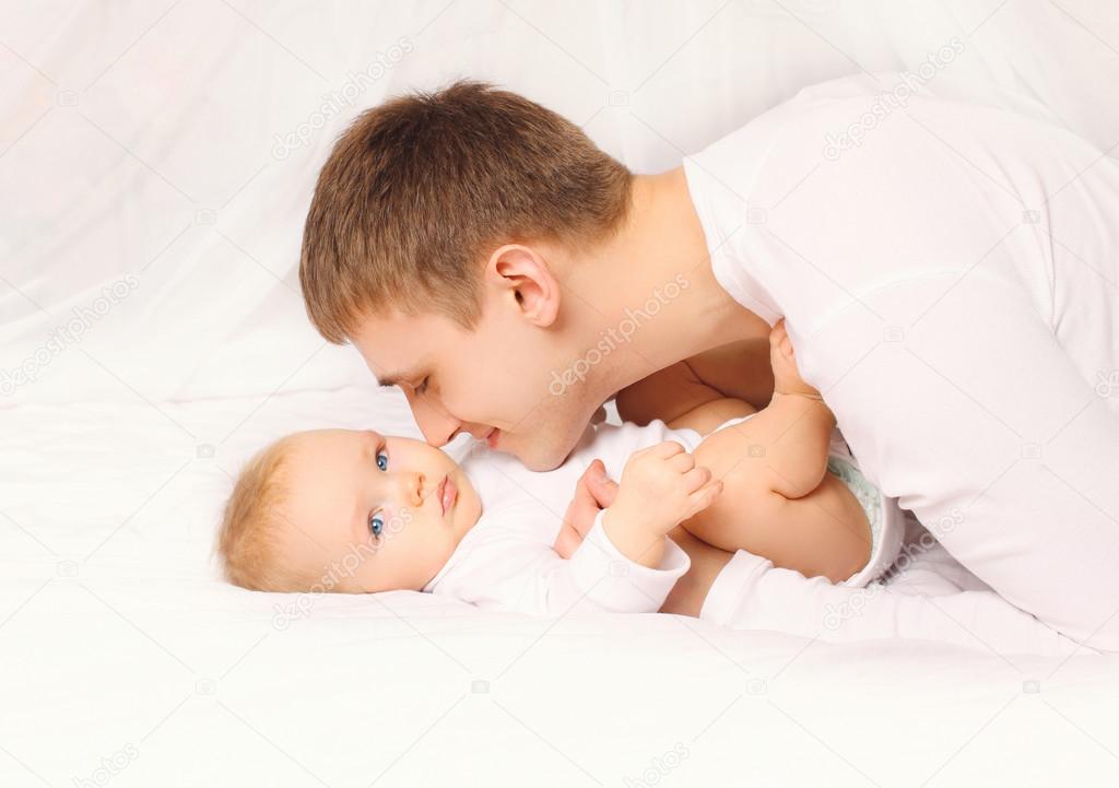 Father and baby at home lying on the bed together bedtime