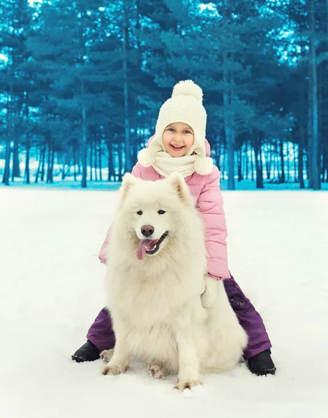 Happy smiling child with white Samoyed dog on snow in winter day — Stock Photo, Image