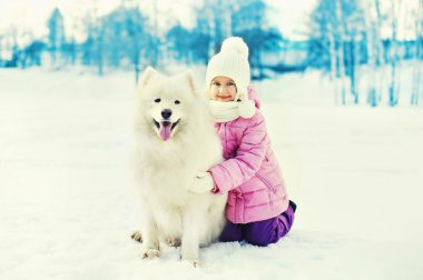 WI karda oynayan beyaz Samoyed köpek ile mutlu gülümseyen çocuk