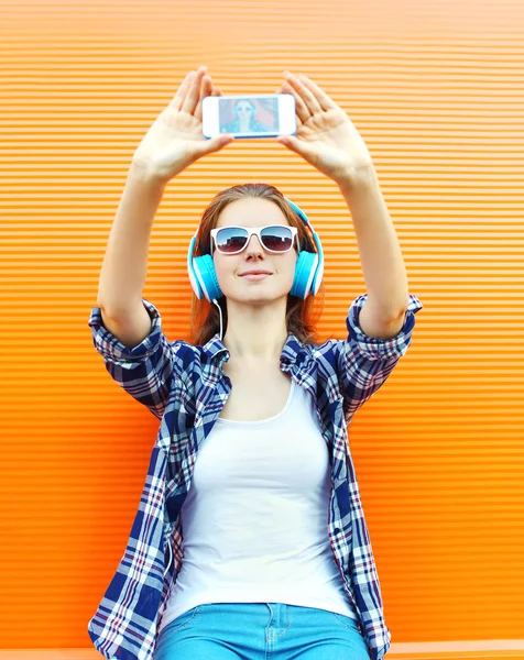 Menina legal faz auto-retrato no smartphone e ouve música — Fotografia de Stock