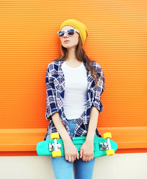 Mode cooles Mädchen mit Skateboard über buntem orangefarbenem Hintergrund — Stockfoto