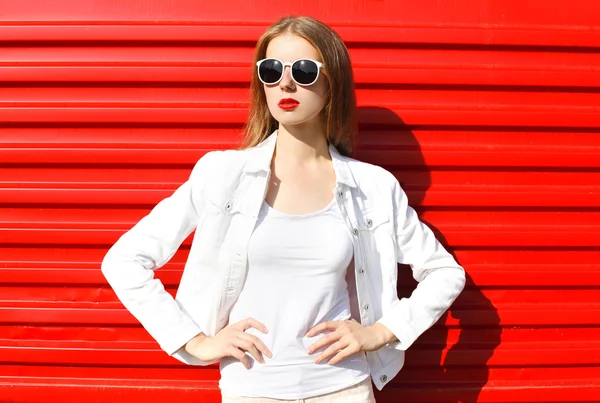 Модная симпатичная женщина в солнцезащитных очках на красном цветном фоне — стоковое фото