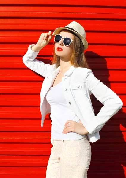 Modèle de femme de mode en lunettes de soleil et chapeau sur le dos coloré rouge — Photo