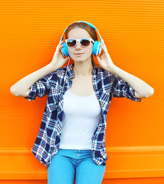 Menina ouve música em fones de ouvido sobre backgro laranja colorido — Fotografia de Stock