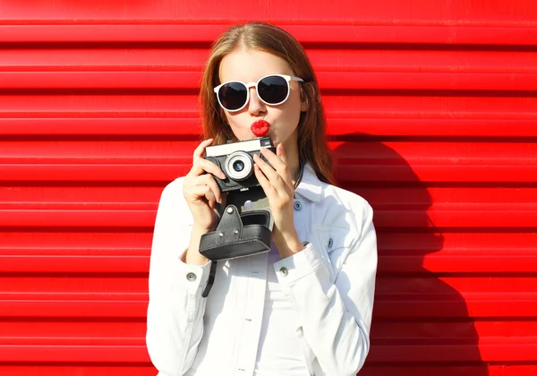 Mujer bastante cool con cámara retro sobre fondo rojo — Foto de Stock