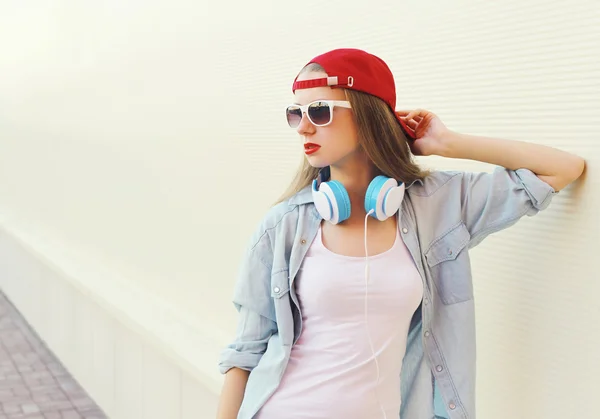 Mooie vrouw in rode Pet en zonnebril met koptelefoon over whit — Stockfoto