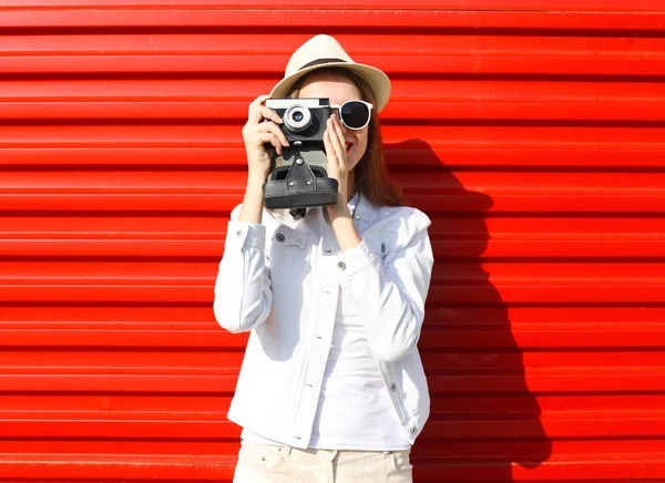 Mulher bonita com câmera retro sobre fundo vermelho — Fotografia de Stock