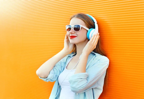 Mulher ouve e gosta de música em fones de ouvido sobre backg colorido — Fotografia de Stock