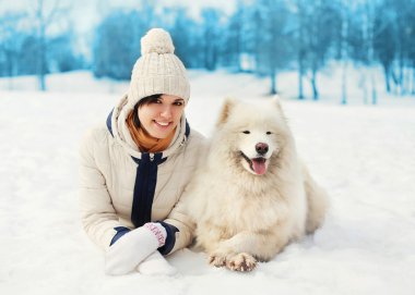 Kış günü kar üzerinde yalan beyaz Samoyed köpek ile kadın sahibi