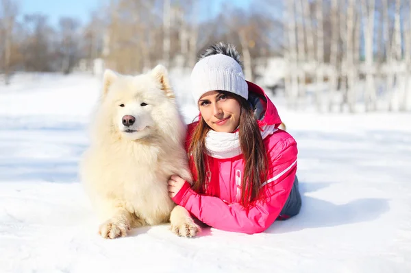 Woman owner with white Samoyed dog lying on snow in winter day — Stock Photo, Image
