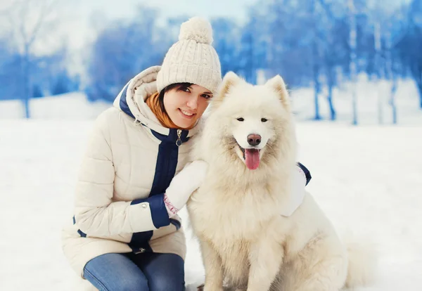 Femme propriétaire étreignant blanc Samoyed chien sur la neige dans la journée d'hiver — Photo