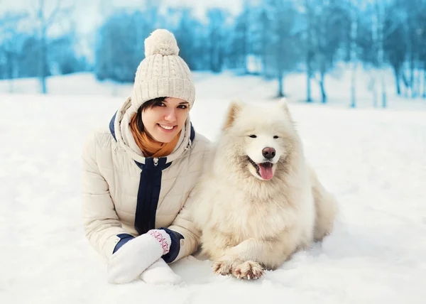 Woman owner with white Samoyed dog lying on snow in winter day — Stock Photo, Image