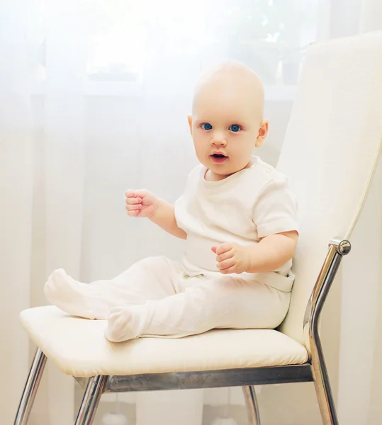 Baby sitting on the chair at home and looks on camera — Stock Photo, Image