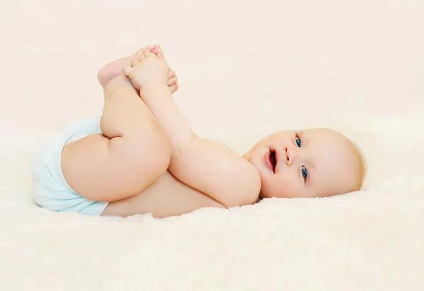 Feliz bebê sorridente deitado brincando na cama em casa — Fotografia de Stock