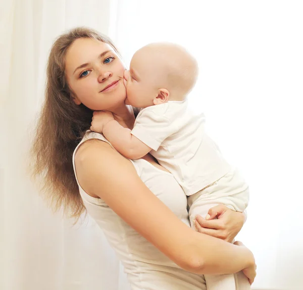 Happy young mother with her baby on hands over window — Stock Photo, Image