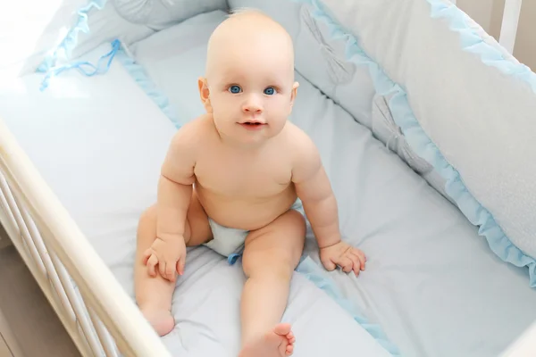 Little baby sitting at home in his bed and looks on camera up — Stock Photo, Image