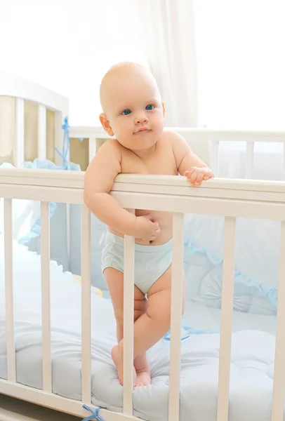 Pequeño bebé de pie en la cama en casa —  Fotos de Stock