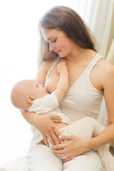 Mother feeding breast her baby at home on chair — Stock Photo, Image