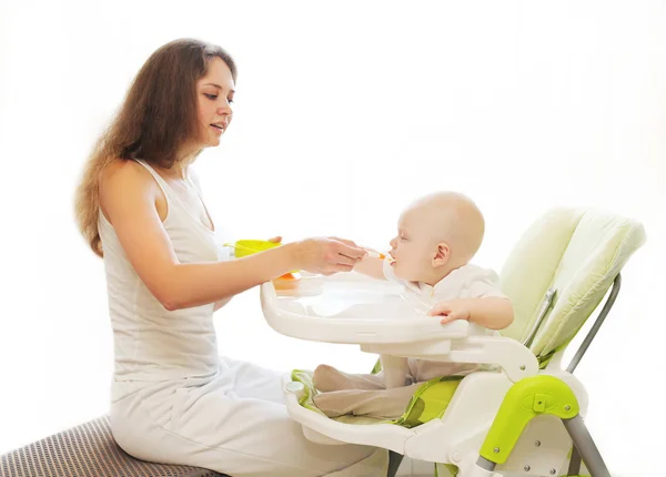 Mutter füttert Baby-Löffel sitzend für Tisch zu Hause — Stockfoto