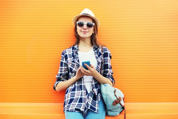 Szép, mosolygós nő használ smartphone város alatt narancssárga háttérben — Stock Fotó