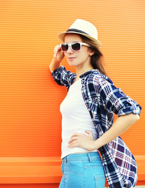 Bella donna che indossa un cappello di paglia e occhiali da sole sulla schiena arancione — Foto Stock