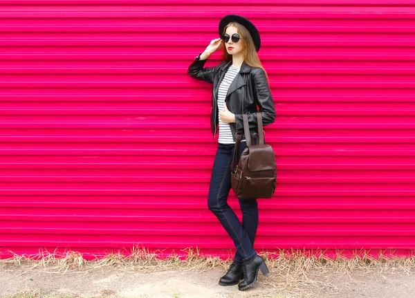 Fashion woman in black rock style posing over colorful pink back