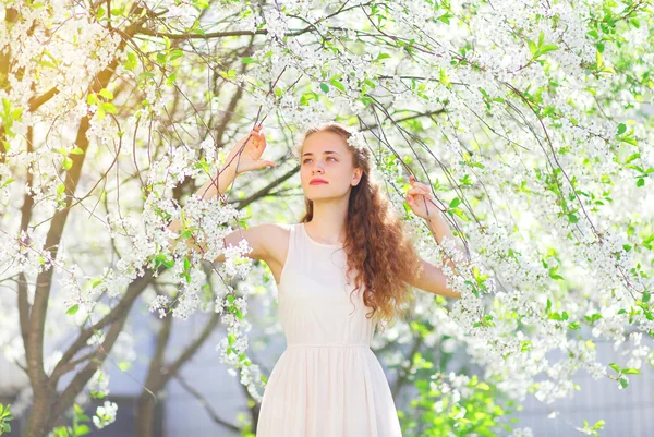 Mooi jong meisje met krullend haar in bloeiende lentetuin — Stockfoto