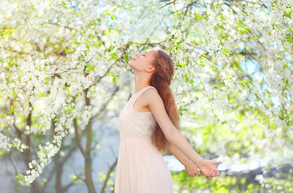 Mooie jonge vrouw genieten van geur in de bloeiende lentetuin — Stockfoto