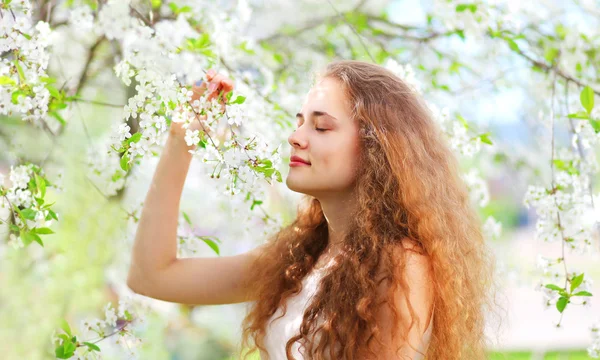 Spring beautiful young girl with curly hair in flowering white g Royalty Free Stock Photos