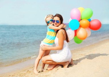 Deniz kenarında plajda renkli balonlar ile sarılma anne çocuk