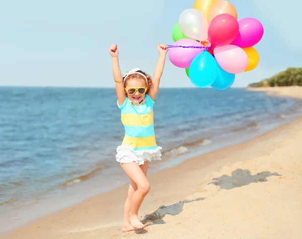 Feliz niño sonriente en la playa jugando con globos de colores cerca — Foto de Stock