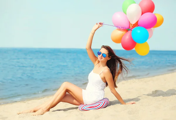 Felice giovane donna con palloncini colorati sulla spiaggia vicino al mare godere — Foto Stock