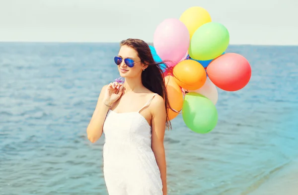 Jovem feliz com balões coloridos na praia sobre o mar desfrutar — Fotografia de Stock