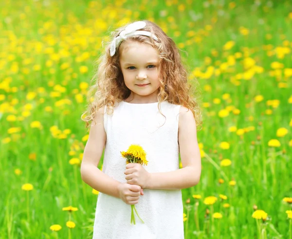 Beautiful little girl child on meadow with yellow dandelion flow — Stock Photo, Image