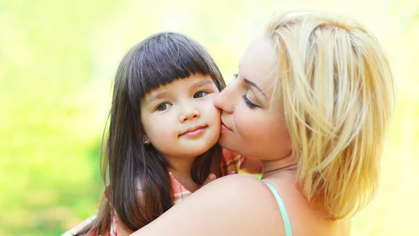 Portrait happy loving mother kissing child outdoors in summer su — Stock Photo, Image