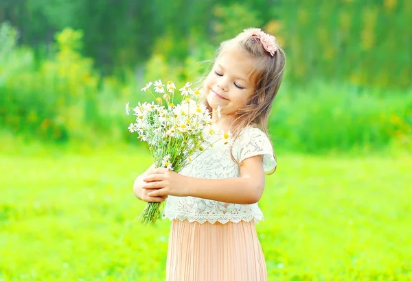 Stående glad liten flicka barn med bukett blommor under våren — Stockfoto
