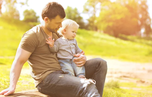 Feliz pai e filho descansando sentados juntos no verão grama — Fotografia de Stock