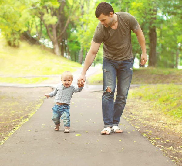 Jovem pai e filho caminhando juntos no parque de verão — Fotografia de Stock