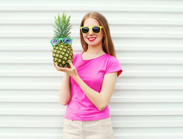 Mode hübsches Mädchen in Sonnenbrille mit Ananas auf weißem Rücken — Stockfoto