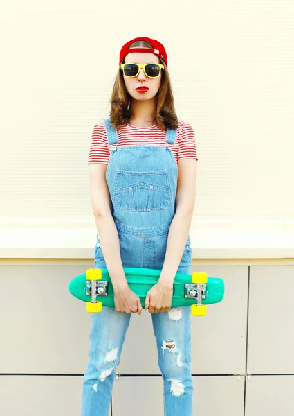 Модный портрет симпатичной девушки с скейтбордом над белой бабой — стоковое фото