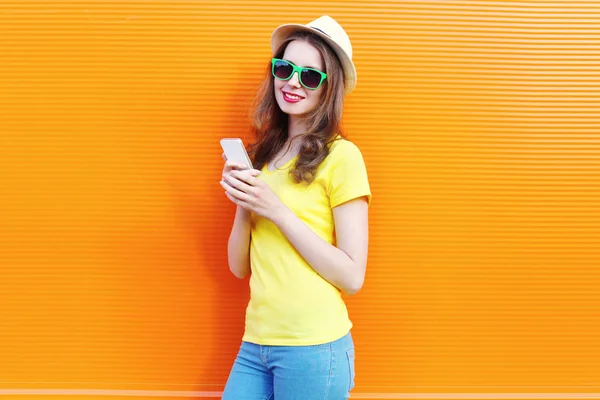 Mujer bonita usando teléfono inteligente sobre fondo naranja colorido — Foto de Stock