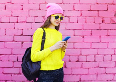 Üzerinde renkli pembe bac Smartphone kullanarak oldukça serin kız moda