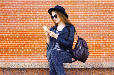 Güzel kadın üzerinde siyah rock tarzı Smartphone kullanarak te tuğla